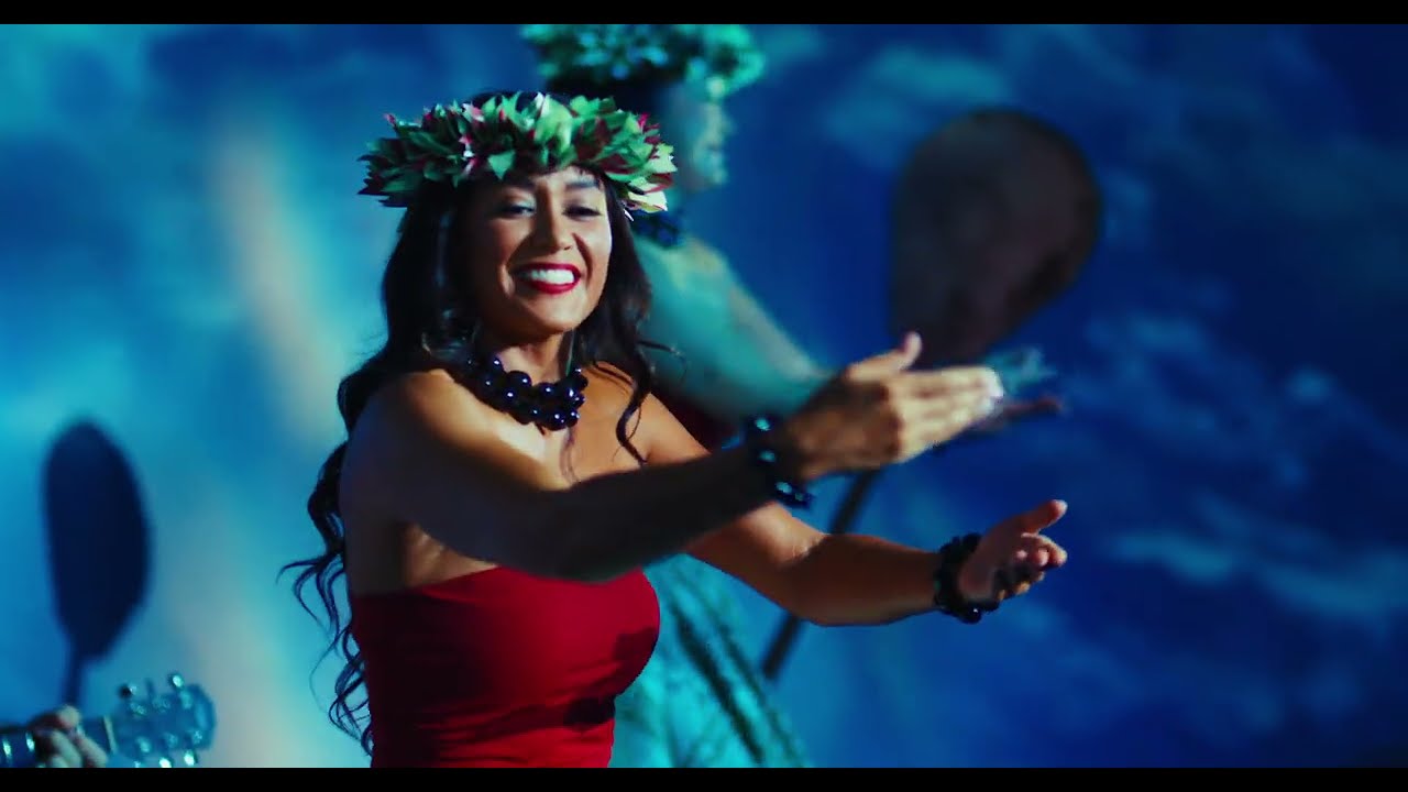 A performer framed by vivid mapped visuals inside the MELE experience.